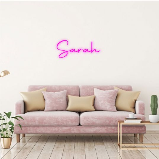 Sarah Name Neon sign by Neon.Outshine  - glowing cursive, displayed on a transparent acrylic base and softly illuminating a chic interior wall.
