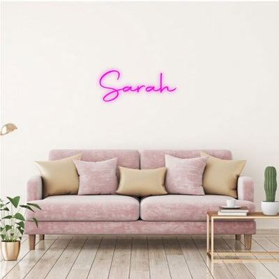 Sarah Name Neon sign by Neon.Outshine  - glowing cursive, displayed on a transparent acrylic base and softly illuminating a chic interior wall.