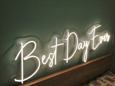 Best Day Ever LED neon sign glowing in white against a floral wedding backdrop   designed by Neon.Outshine for celebrations and events.