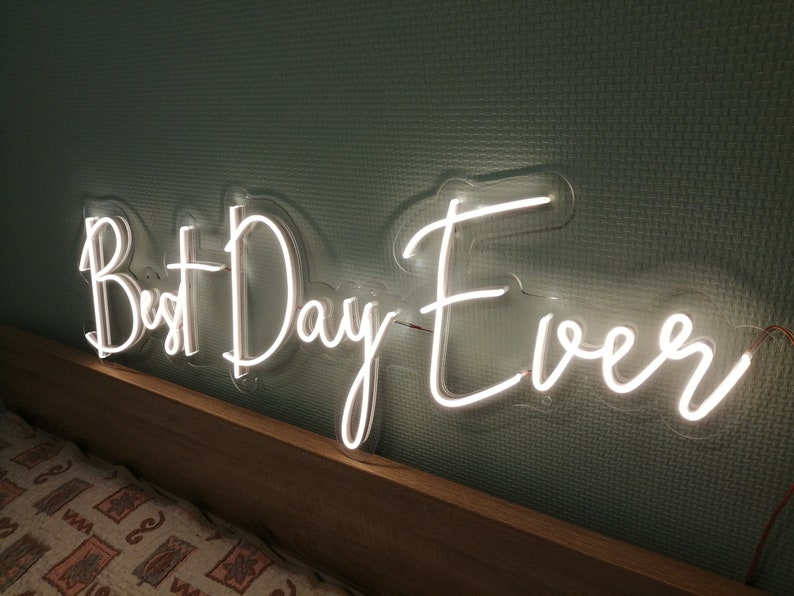 Best Day Ever LED neon sign glowing in white against a floral wedding backdrop   designed by Neon.Outshine for celebrations and events.