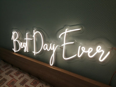 Best Day Ever LED neon sign glowing in white against a floral wedding backdrop   designed by Neon.Outshine for celebrations and events.