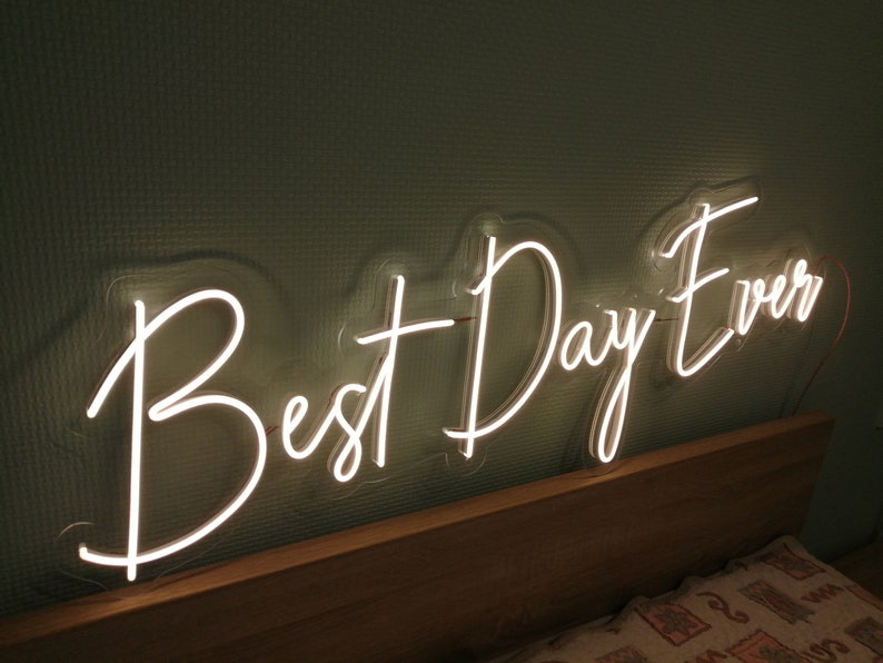 Best Day Ever LED neon sign glowing in white against a floral wedding backdrop   designed by Neon.Outshine for celebrations and events.