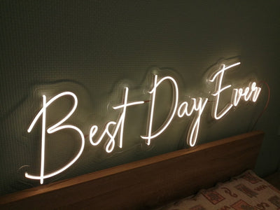 Best Day Ever LED neon sign glowing in white against a floral wedding backdrop   designed by Neon.Outshine for celebrations and events.