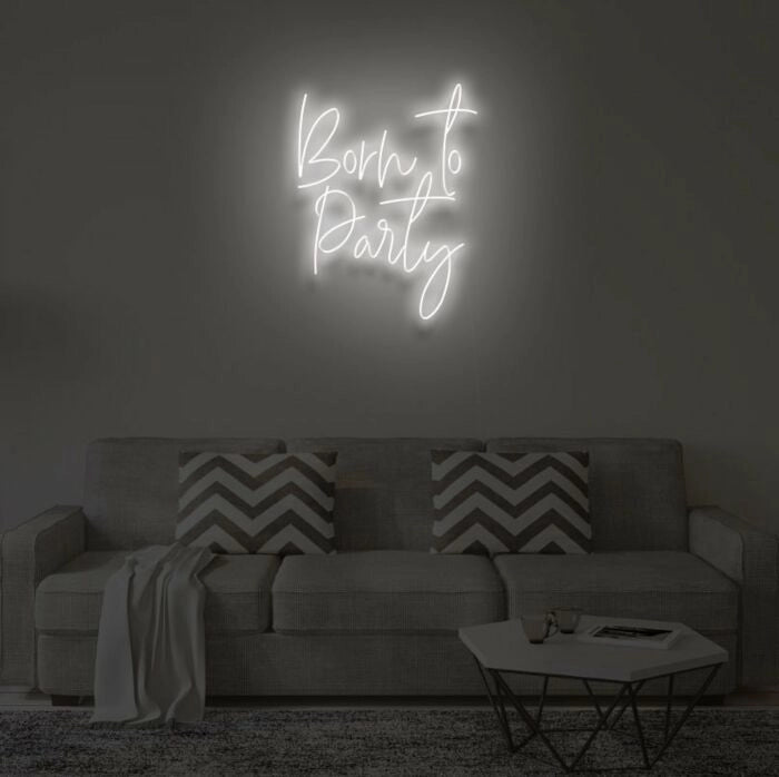 Born To Party LED neon sign glowing in vibrant colors, mounted on a wall in a party setting - Neon.Outshine 