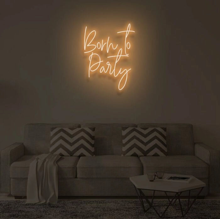 Born To Party LED neon sign glowing in vibrant colors, mounted on a wall in a party setting - Neon.Outshine 