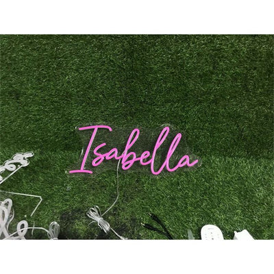 Isabella Name Neon sign By Neon.Outshine - in elegant script, casting a soft pink light on a bedroom wall.