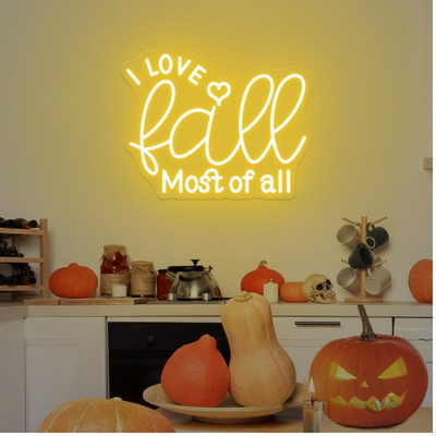 Love Fall Most of All neon sign in glowing on clear acrylic backing by Neon.outshine, set in cozy autumn decor setting.