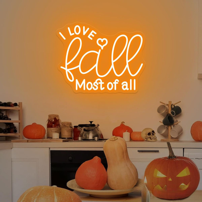 Love Fall Most of All neon sign in glowing on clear acrylic backing by Neon.outshine, set in cozy autumn decor setting.