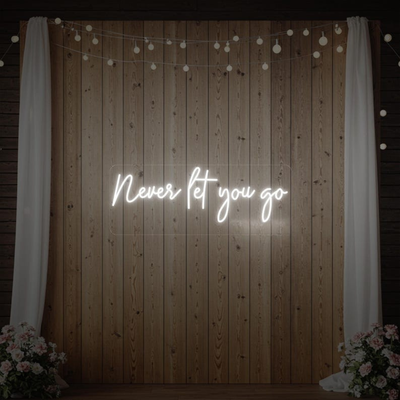 Never Let You Go Wedding Neon Sign by Neon.Outshine glowing beautifully behind a romantic wedding reception setup.