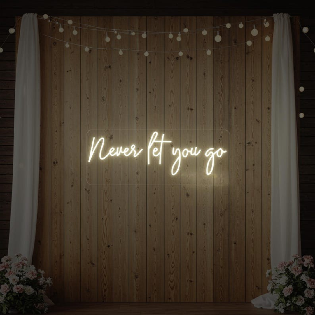 Never Let You Go Wedding Neon Sign by Neon.Outshine glowing beautifully behind a romantic wedding reception setup.