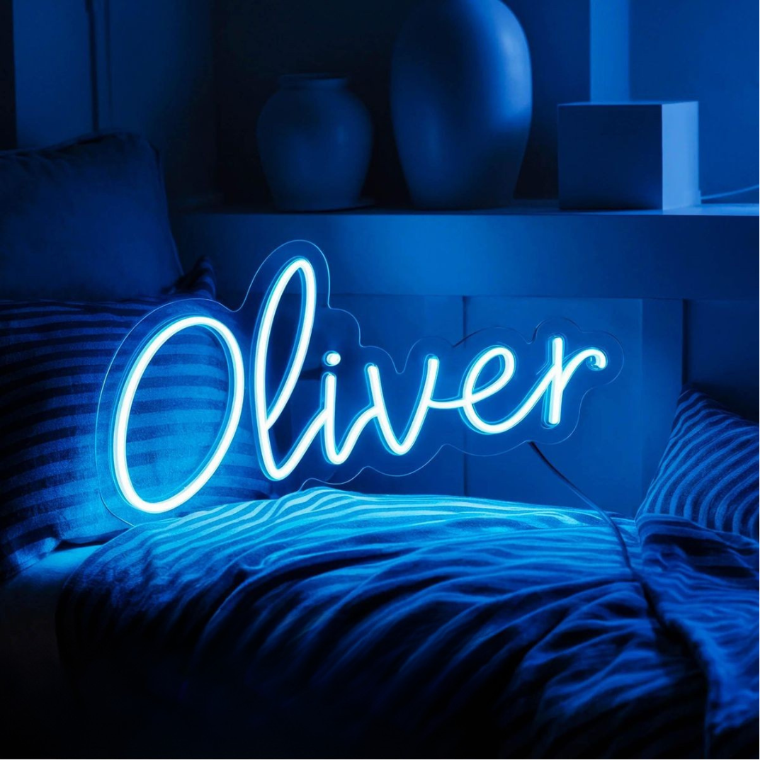 Oliver Name Neon sign by Neon.Outshine. - in vibrant glowing letters, mounted on a clear acrylic sheet and illuminating a cozy modern interior.