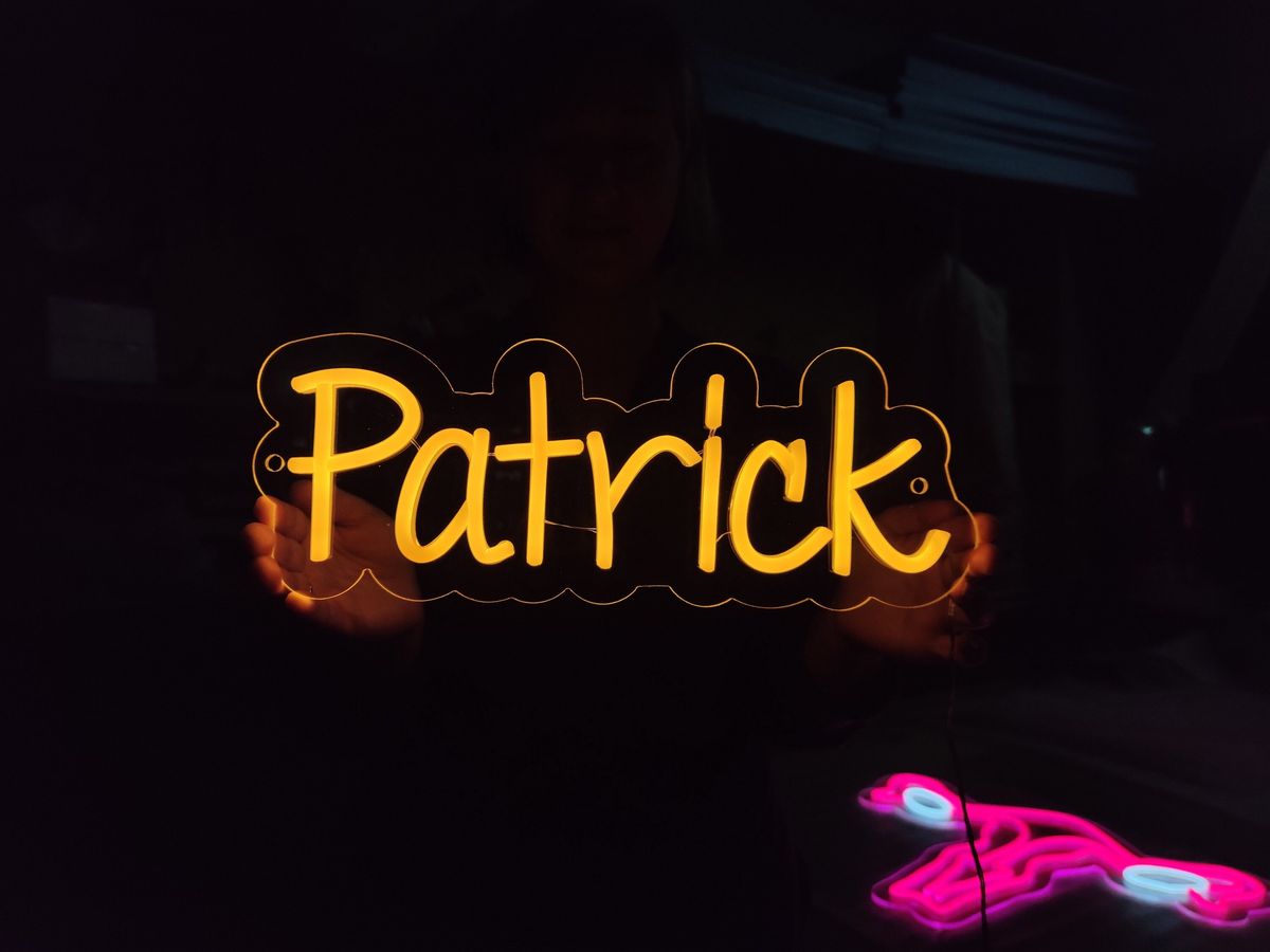 Patrick Name Neon sign glowing in warm white on bedroom wall - Neon.Outshine 