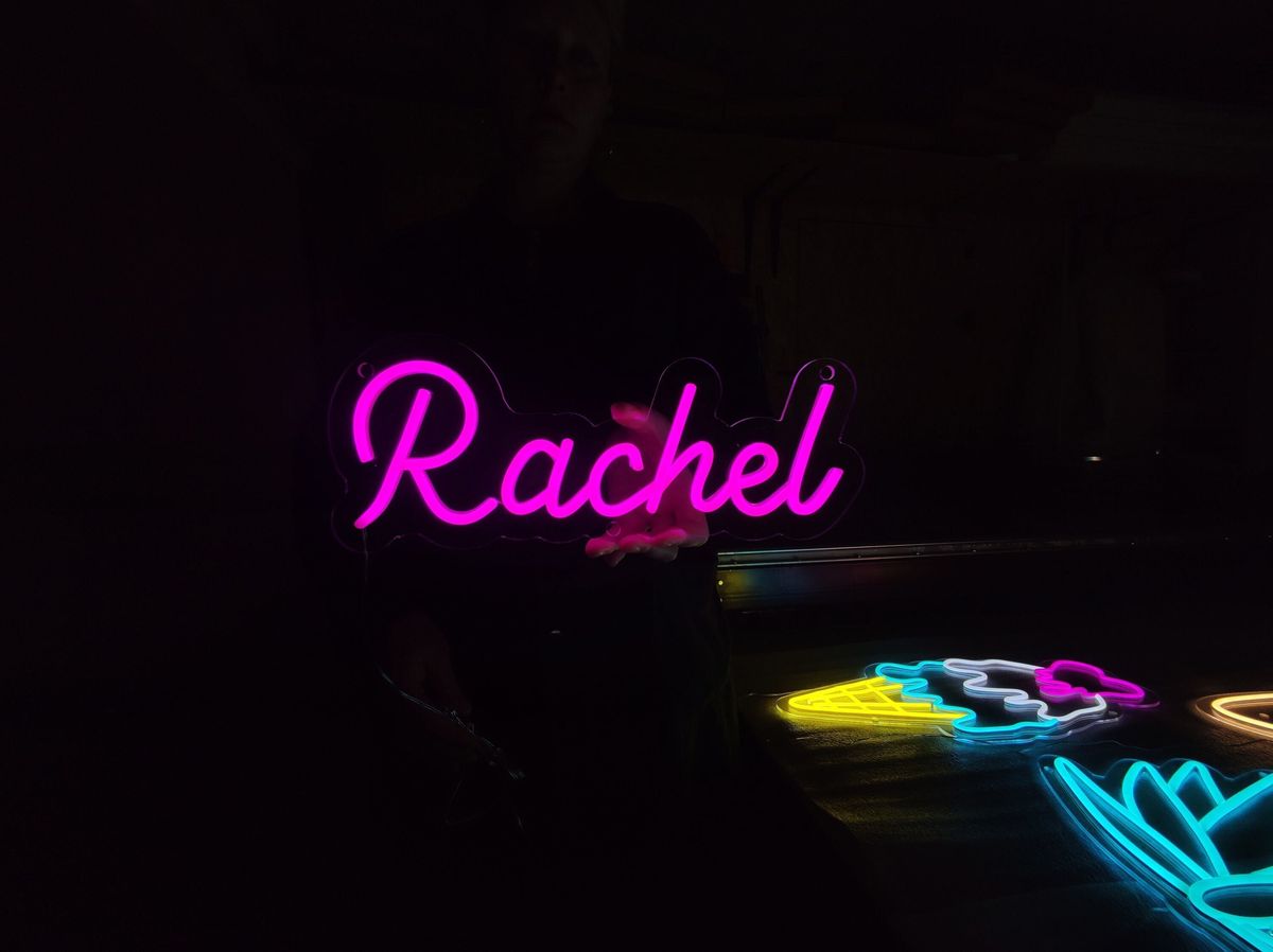 Rachel Name Neon sign in glowing purple script font, mounted on clear acrylic, perfect for modern room or event decor - Neon.Outshine 