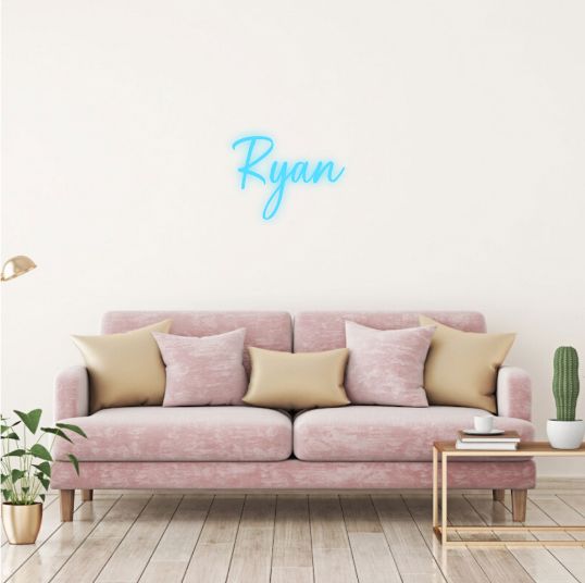 Ryan Name Neon sign in stylish script, mounted on a clear acrylic panel and radiating vibrant light against a modern interior wall - Neon.Outshine 