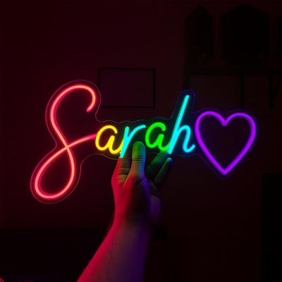 Sarah Name Neon sign by Neon.Outshine  - glowing cursive, displayed on a transparent acrylic base and softly illuminating a chic interior wall.