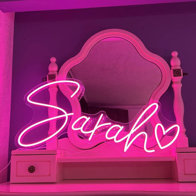 Sarah Name Neon sign by Neon.Outshine  - glowing cursive, displayed on a transparent acrylic base and softly illuminating a chic interior wall.