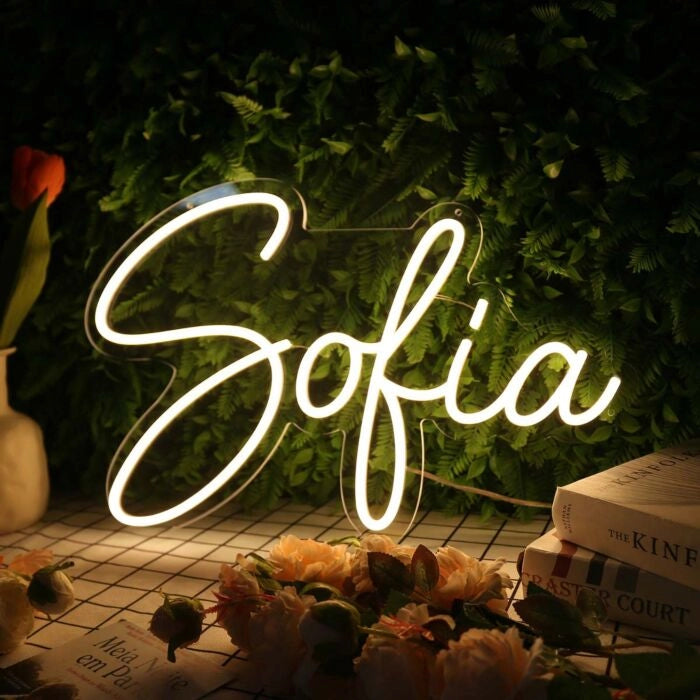  by Neon.Outshine - in glowing cursive letters, mounted on clear acrylic and softly lighting a feminine, modern interior.