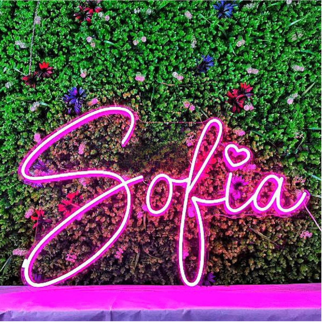 Sofia Name Neon sign by Neon.Outshine - in glowing cursive letters, mounted on clear acrylic and softly lighting a feminine, modern interior.