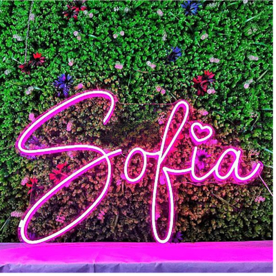 Sofia Name Neon sign by Neon.Outshine - in glowing cursive letters, mounted on clear acrylic and softly lighting a feminine, modern interior.