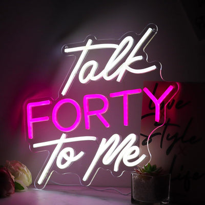 Talk Forty To Me LED neon sign in hot pink, glowing on a party wall  - designed by Neon.Outshine for 40th birthday celebrations.