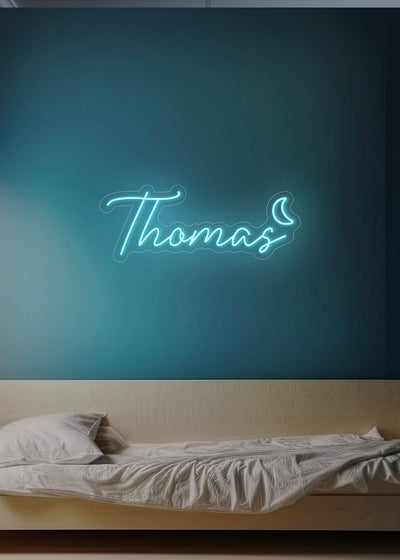 Thomas Name Neon sign by Neon.Outshine - in bold, vibrant script, mounted on a clear acrylic background and lighting up a stylish room.