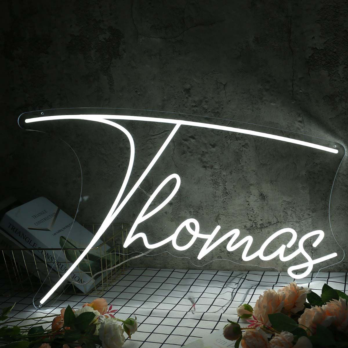 Thomas Name Neon sign by Neon.Outshine - in bold, vibrant script, mounted on a clear acrylic background and lighting up a stylish room.