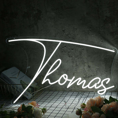 Thomas Name Neon sign by Neon.Outshine - in bold, vibrant script, mounted on a clear acrylic background and lighting up a stylish room.