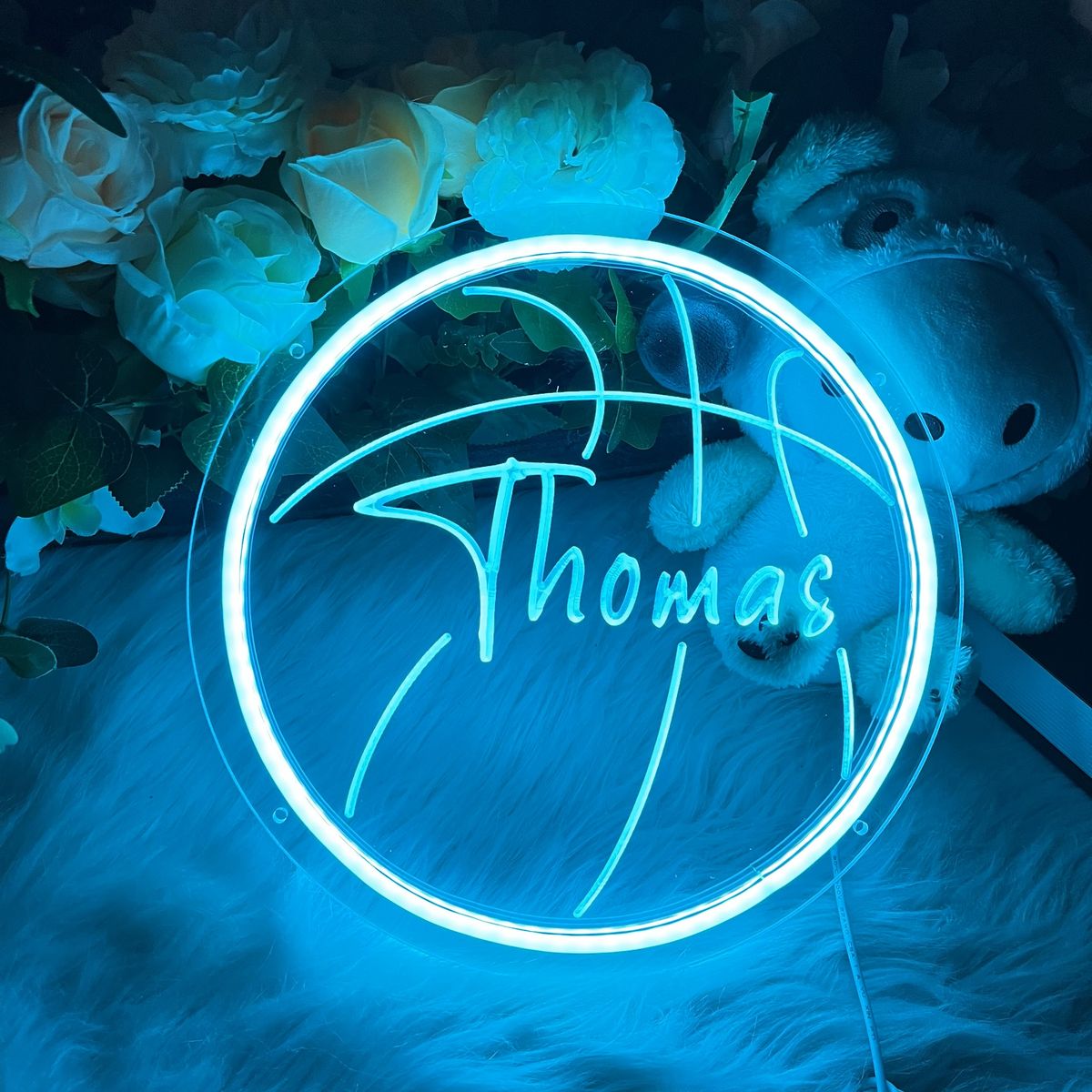 Thomas Name Neon sign by Neon.Outshine - in bold, vibrant script, mounted on a clear acrylic background and lighting up a stylish room.