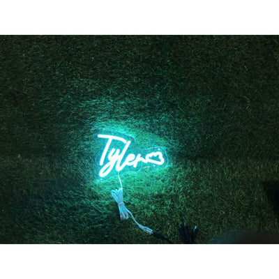 Tyler' LED neon sign glowing in blue, mounted on a dark wall – by Neon.Outshine.
