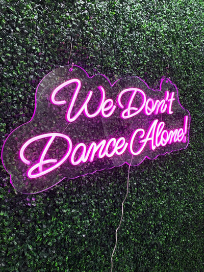 We Don’t Dance Alone neon sign in vivid LED glow, mounted on acrylic, lighting up a party or dance space – by Neon.Outshine.