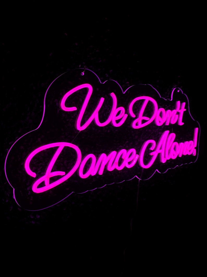 We Don’t Dance Alone neon sign in vivid LED glow, mounted on acrylic, lighting up a party or dance space – by Neon.Outshine.